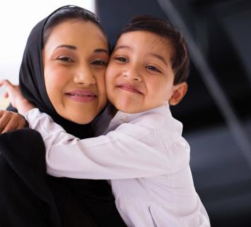 Smiling lady in a hijab hugging her son