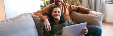 Man and woman on a sofa looking at a laptop
