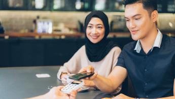 Man using cardless payment sat next to smiling woman