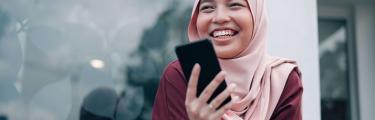 Woman with mobile phone sat near window - personal checking accounts
