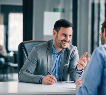 Man in a suit laughing sitting at a desk