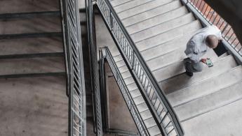 Man in a white shirt walking up a stairwell holding his phone