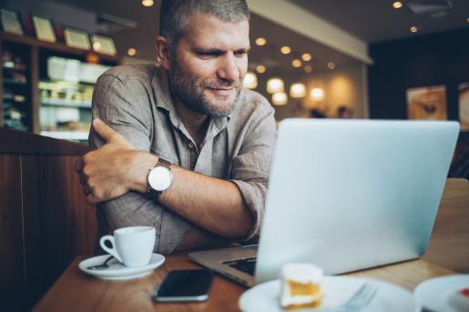 Man looking at laptop with and espresso in a coffee shop