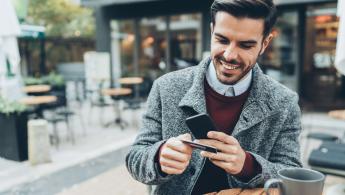 Man in a grey trenchcoat using his phone for online banking