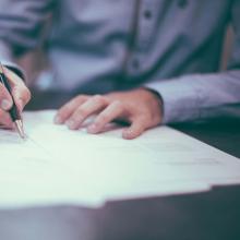 Man using black and gold pen to write on paper.