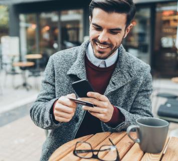Man in a grey trenchcoat using his phone for online banking